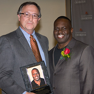 Dan Svedarsky presents Huggins a plaque during his induction into the Athletic Hall of Fame