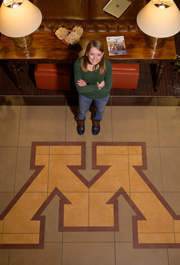 Karlie Brekken standing by a block M logo in the floor in Hertiage Hall