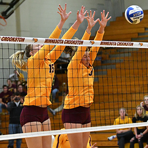 Lauren Wallace going up for a block during a volleyball game with her teammate.