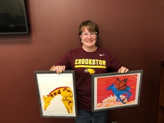 Vanessa Robbins holding two paintings she gifted to UMN Crookston