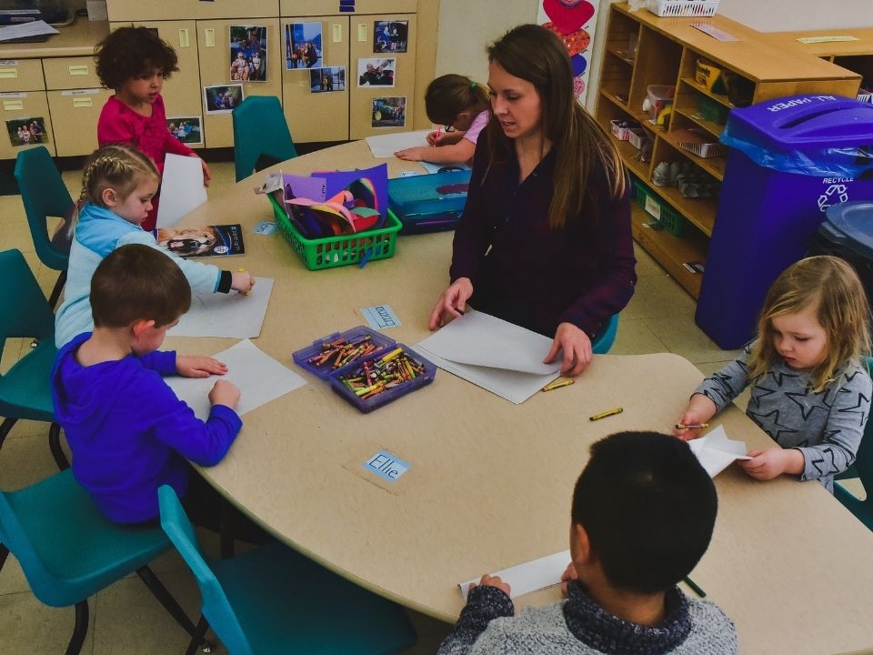 Early Childhood Development Center student staff at a table with children coloring.