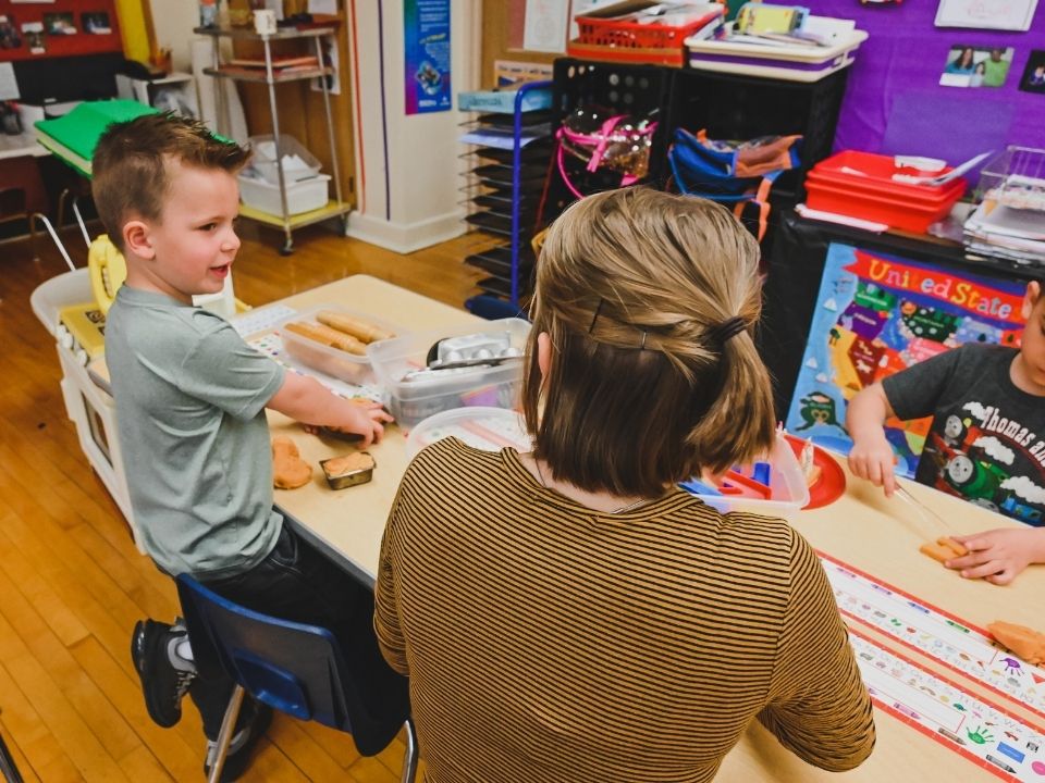 Elementary Teacher in classroom talking with a young student.