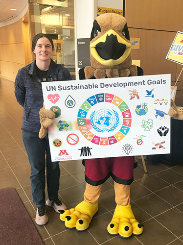 Katy Chapman with Regal the Eagle holding the UN Sustainable Development Goals poster