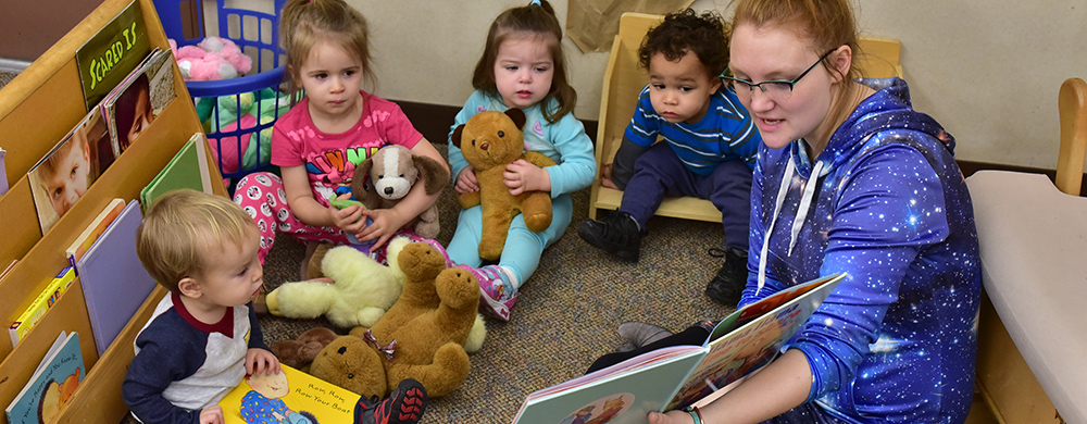 ECDC staff reading a book to a group of toddlers