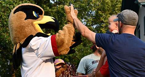 Regal the Eagle high fiving a dad and baby during the Ox Cart Days Torchlight Parade