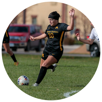 Golden Eagle Soccer player kicking the ball away from an opponent on the UMC home soccer field