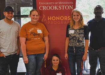 A group of students standing by the Honors Program banner