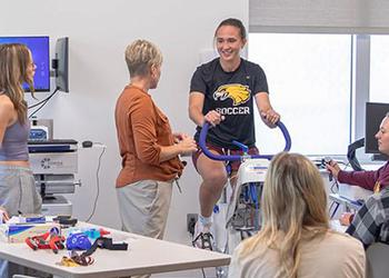 Faculty member having a student demonstrate on an exercise bike during class