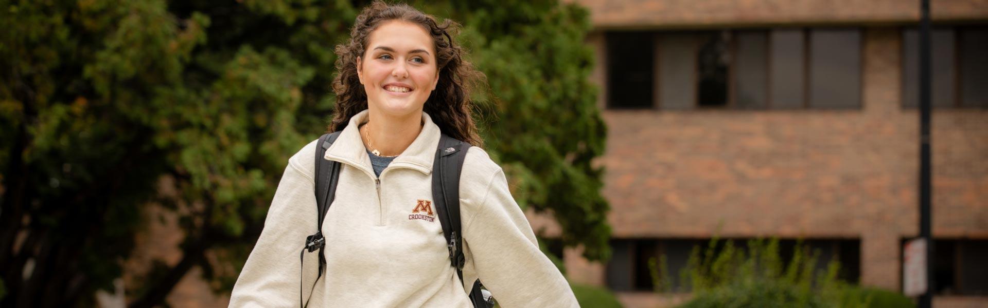 Female student walking with a smile outside Hill Hall