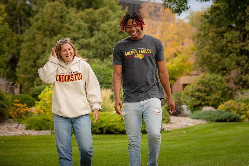 Two students walking and smiling on the Campus Mall