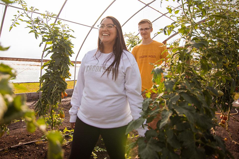 Two smiling students walking through the UMCrookston Greenhouse