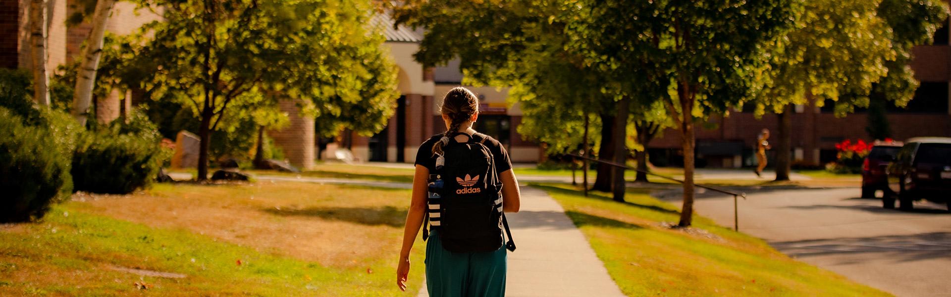 Student walking outside of Dowell Hall during the late summer