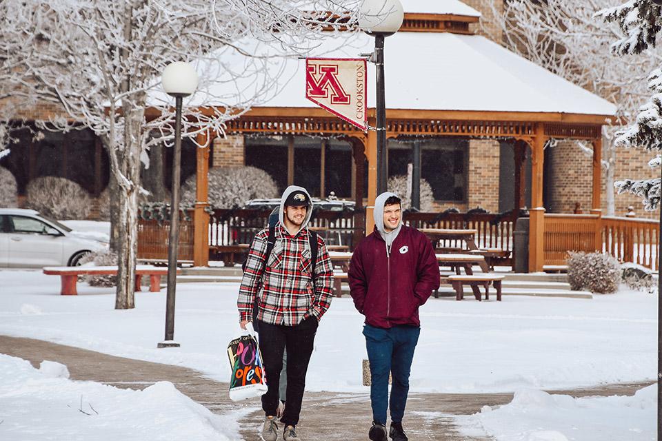 Beautiful snowy day on the UMN Crookston campus mall - two male students walking holding a bookstore bag