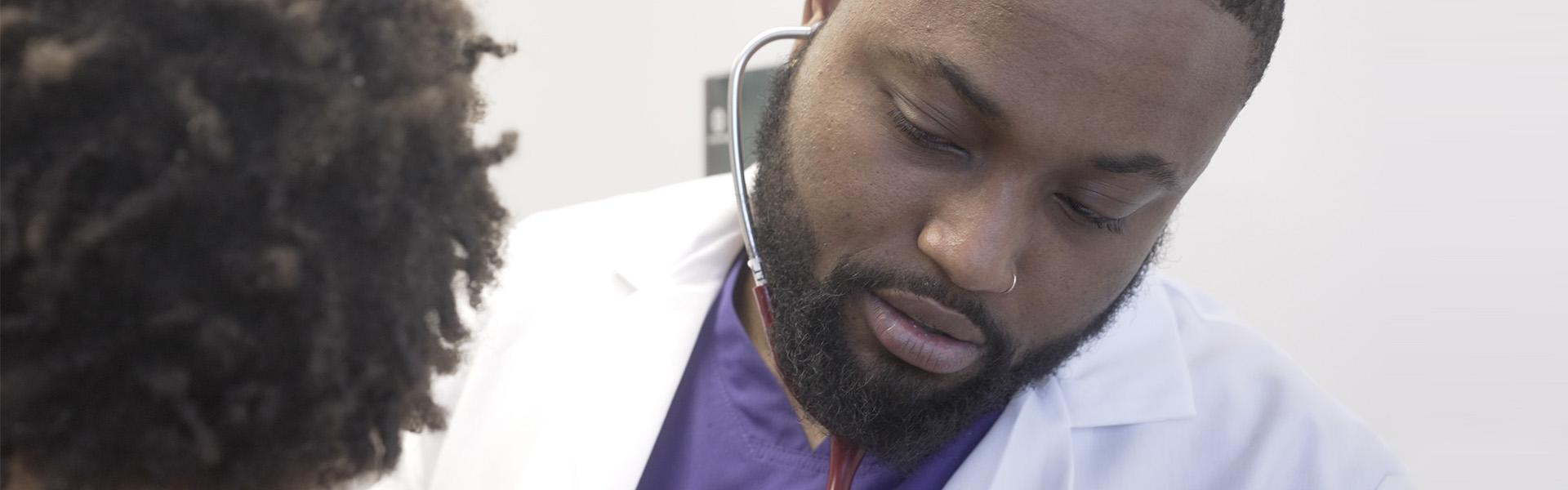 A doctor using his stethoscope on a patient