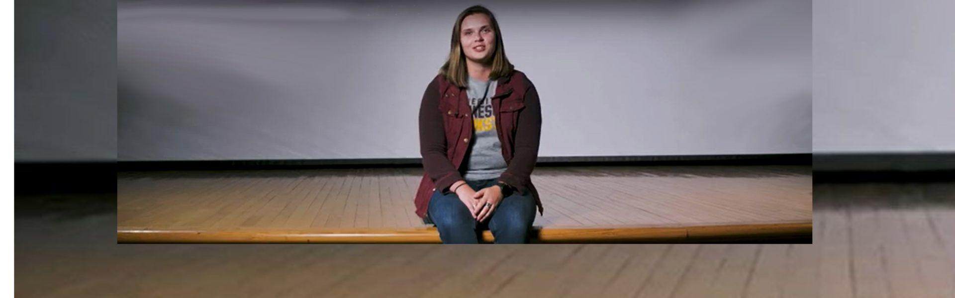 Eleora DeMuth sitting on the Kiehle Auditorium stage