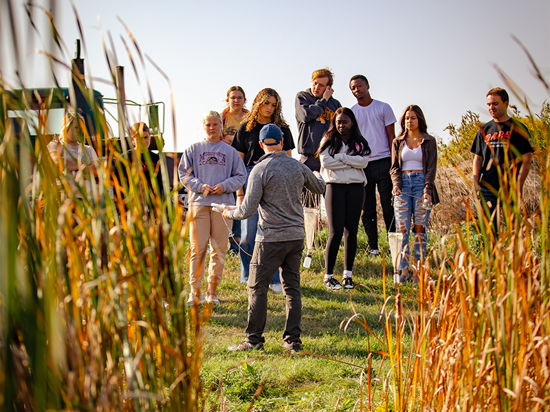 Biology instructor took a class of students to a pond to take some samples and learn about the environment