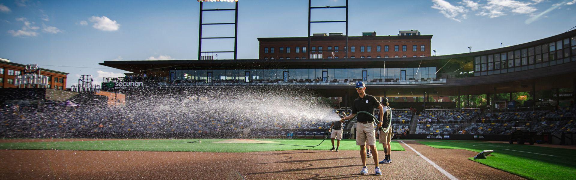 Man spraying the baseball field with water