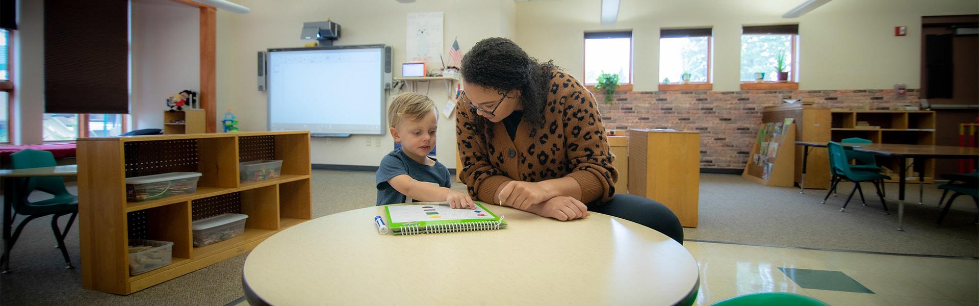 Early Education student working with a young boy at a table in the Early Childhood Development Center