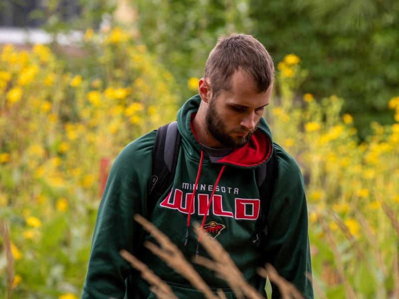 Student strolling around the UMC Nature Nook in the tall prairie grass and wildflowers