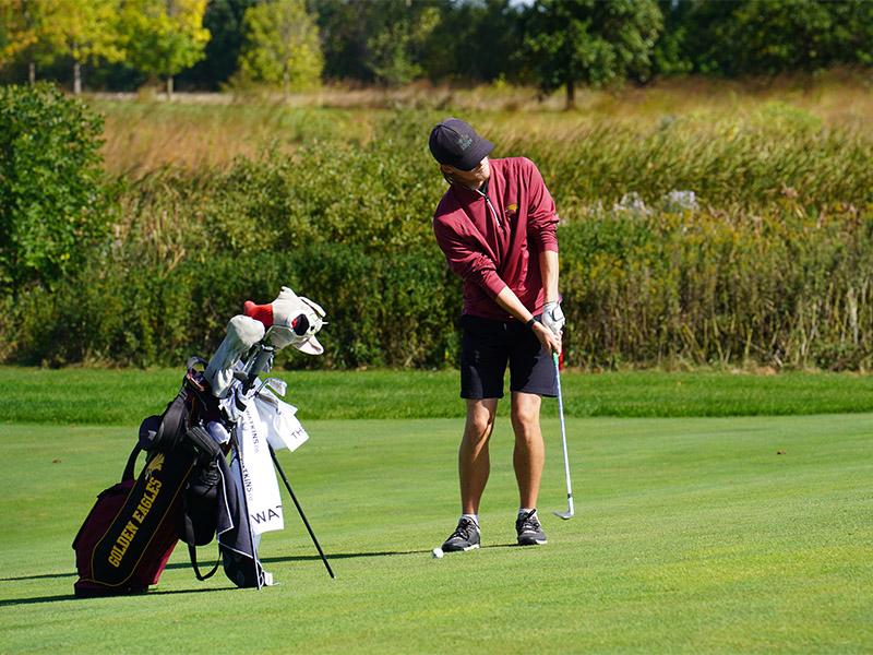 Golden Eagle men's golfer chipping the ball on to the green