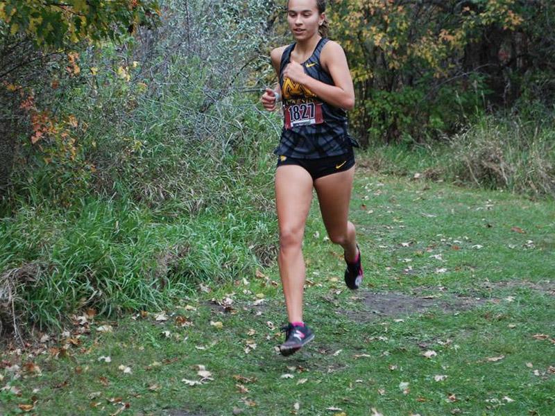 Golden Eagle women's cross country runner on a grassy path