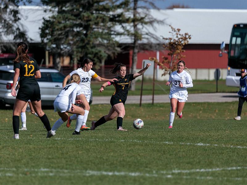 Golden Eagle soccer player kicking the ball between several opposing players