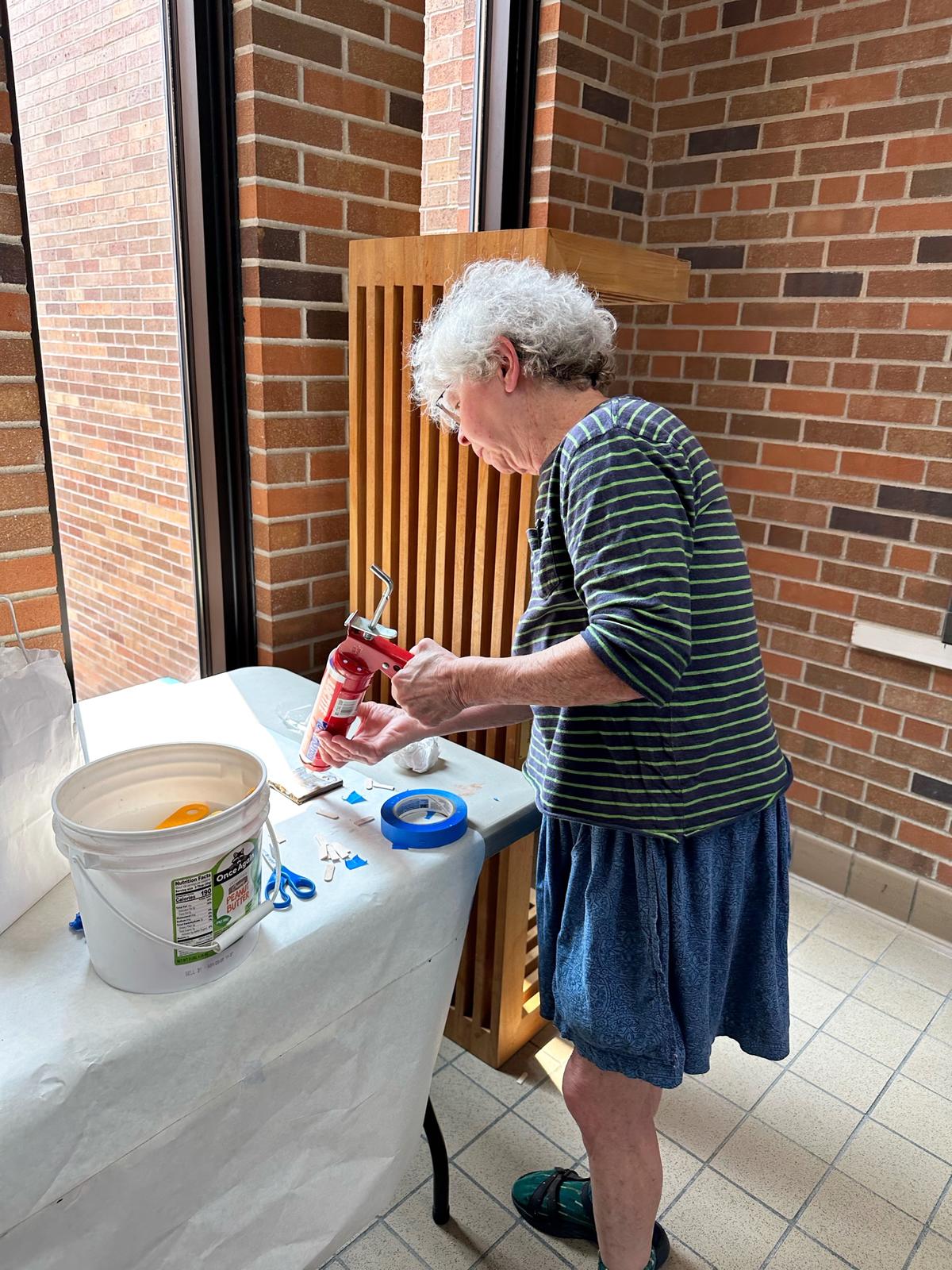 Artist Susan Warner adds adhesive to a tile before installation in Dowell Hall