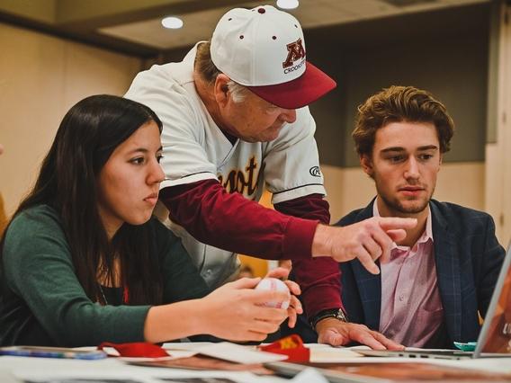 Faculty member pointing something out on a laptop to two students