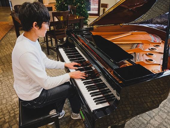 International student playing at a grand piano in Evergreen Hall