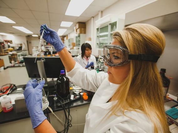 Student working in a lab with a pipet and beaker