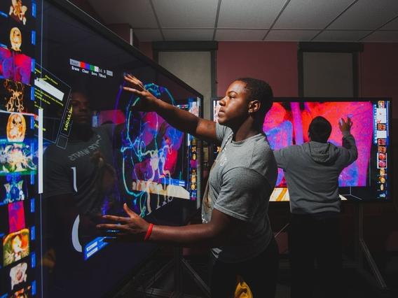 Student manipulating a health related image on a giant computer touch screen