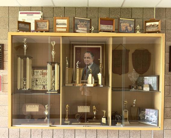 Glass display case in the Sports Center that features award plaques, trophies, photos, and other memorabilia from the Northwest School of Agriculture Aggies, University of Minnesota Technical Institute Trojans, and the University of Minnesota Crookston Golden Eagles. 