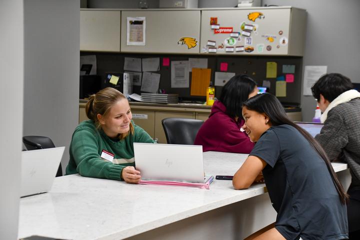 Two female students smiling while looking at a laptop screen