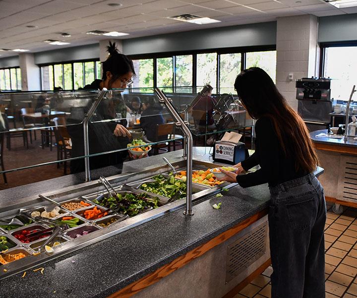 A women getting food at a salad bar. 