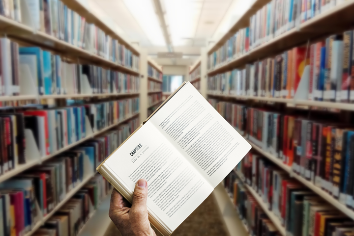 A person holding up a book in the library