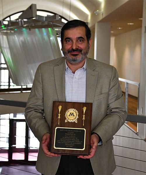 Ali Saeedi holding his U of M Crookston Distinguished Scholar plaque in the Northern Lights Lounge