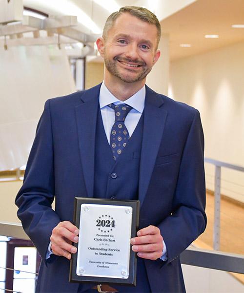 Chris Ehrhart holding his 2024 Outstanding Service to Students plaque in Sargeant Student Center