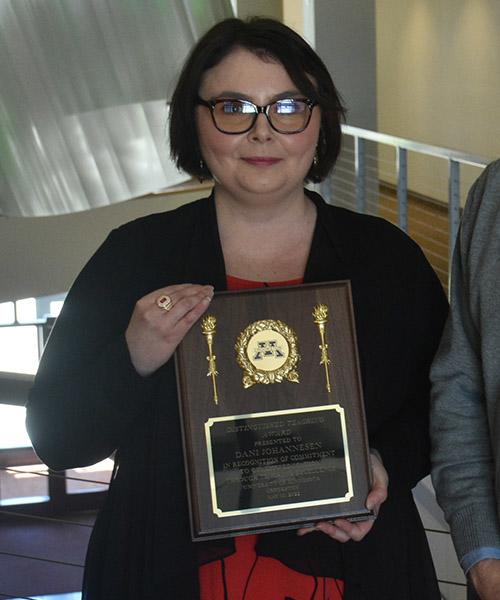 Danielle Johannesen holding her Distinguished Teaching Plaque near the Northern Lights Lounge