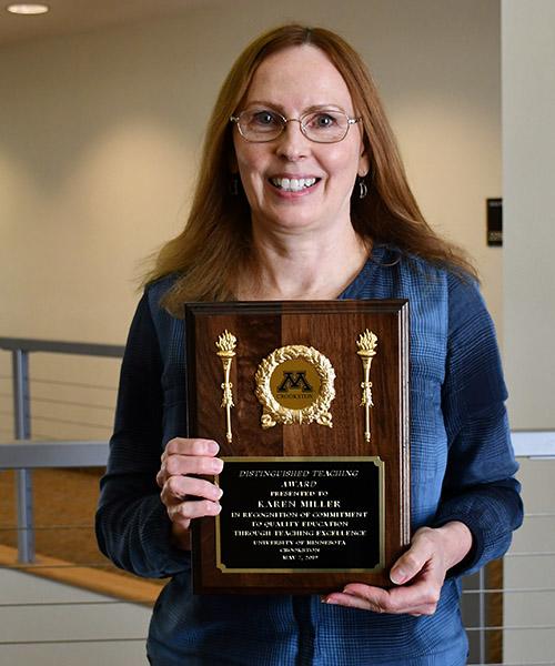 Karen Miller holding her Distinguished Teaching plaque near the Northern Lights Lounge