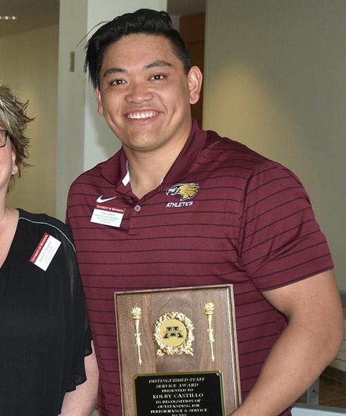 Kolby Castillo holding his Distinguished Staff award plaque