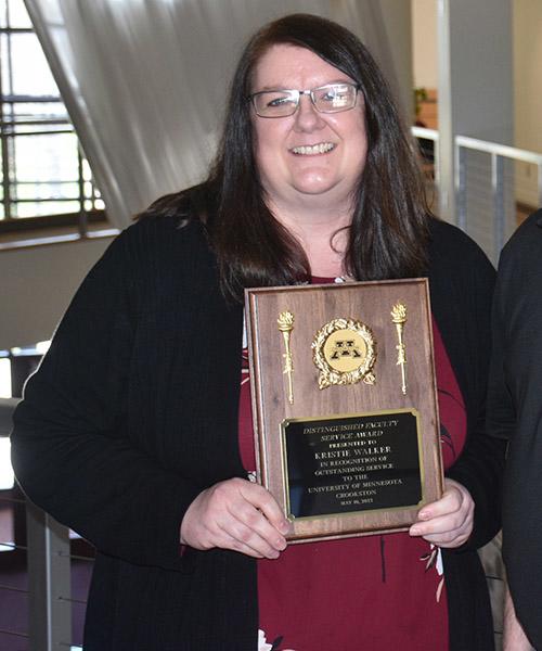 Kristina Walker holding her Distinguished Teaching plaque near the Northern Lights Lounge 2nd floor