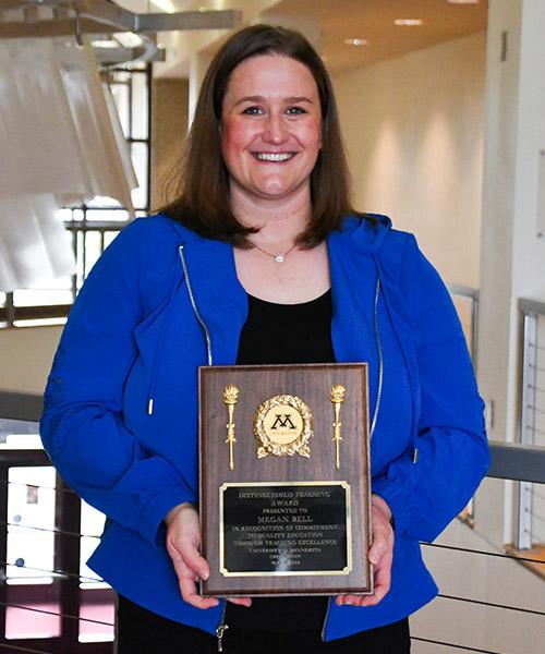 Megan Bell holding her Distinguished Teaching award plaque outside of the Northern Lights Lounge