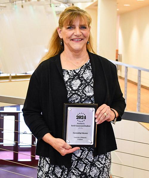 Terrill Bradford holding her 2024 Outstanding Educator Plaque in Sargeant Student Center