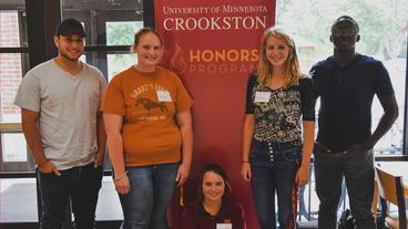 A group of students standing by the Honors Program banner