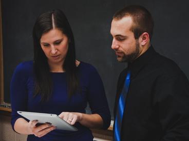 Faculty member speaking with a student and looking an at iPad