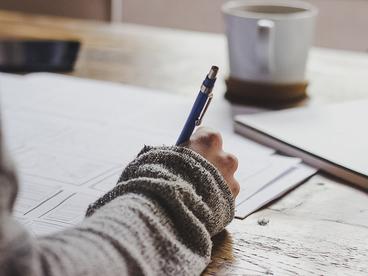 Someone writing at a table with coffee