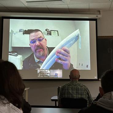 Chad Hornbaker holding a piece of elephant tusk on a Zoom call with U of M Crookston Natural Resources students