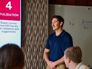 Male student giving a presentation in the Business Board Room