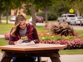 A student sitting at a picnic table outside of Sargeant Student Center
