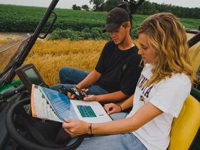 Two students in a Gator looking at precision ag maps in a field